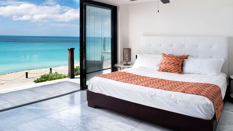 a double bed beside a floor-to-ceiling sliding glass door leading to a private beach in beachcomber at tamarind hills resort and villas