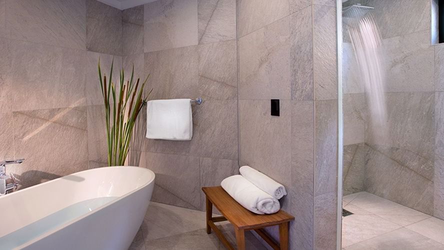 Modern bathroom with a freestanding tub, rainfall shower, and stone finishes, blending luxury and relaxation in a serene, spa-like setting.