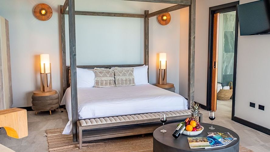 Elegant bedroom with a four-poster bed, warm lighting, and coastal decor, offering a cozy retreat with access to private outdoor views.