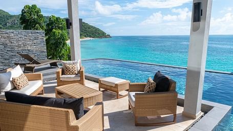 Stylish outdoor lounge area beside an infinity pool, overlooking the turquoise Caribbean Sea and lush hillside of Tamarind Hills.