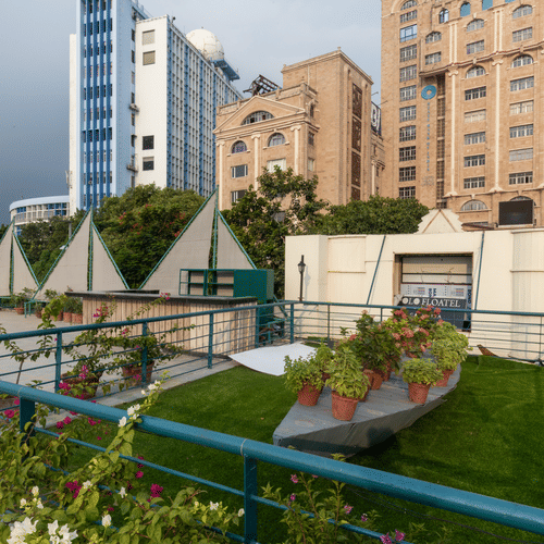 the lawn area with green grass and a boat shaped thing with potted plants on it at Polo Floatel Kolkata