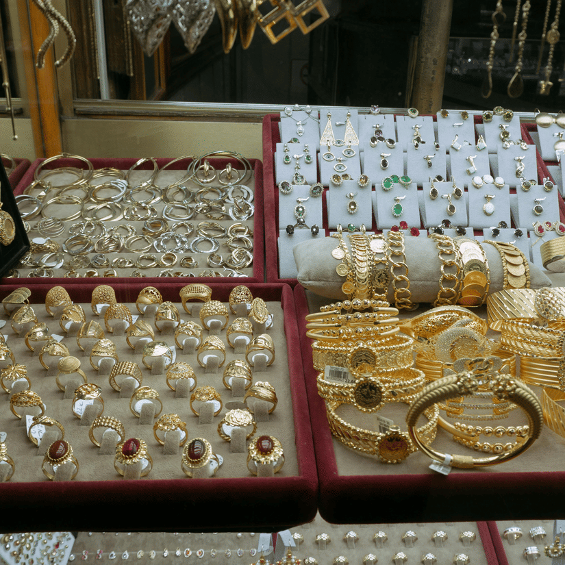 A close-up shot of a display case filled with a variety of gold and silver jewellery, including bangles and bracelets at Souq Waqif Gold Market.