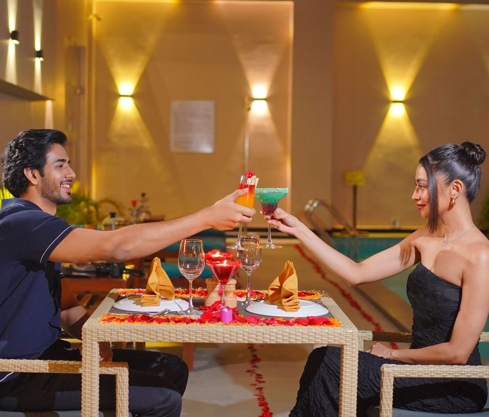 A couple clinking glasses on a rooftop dining space near the pool - Polo Hotel Agartala