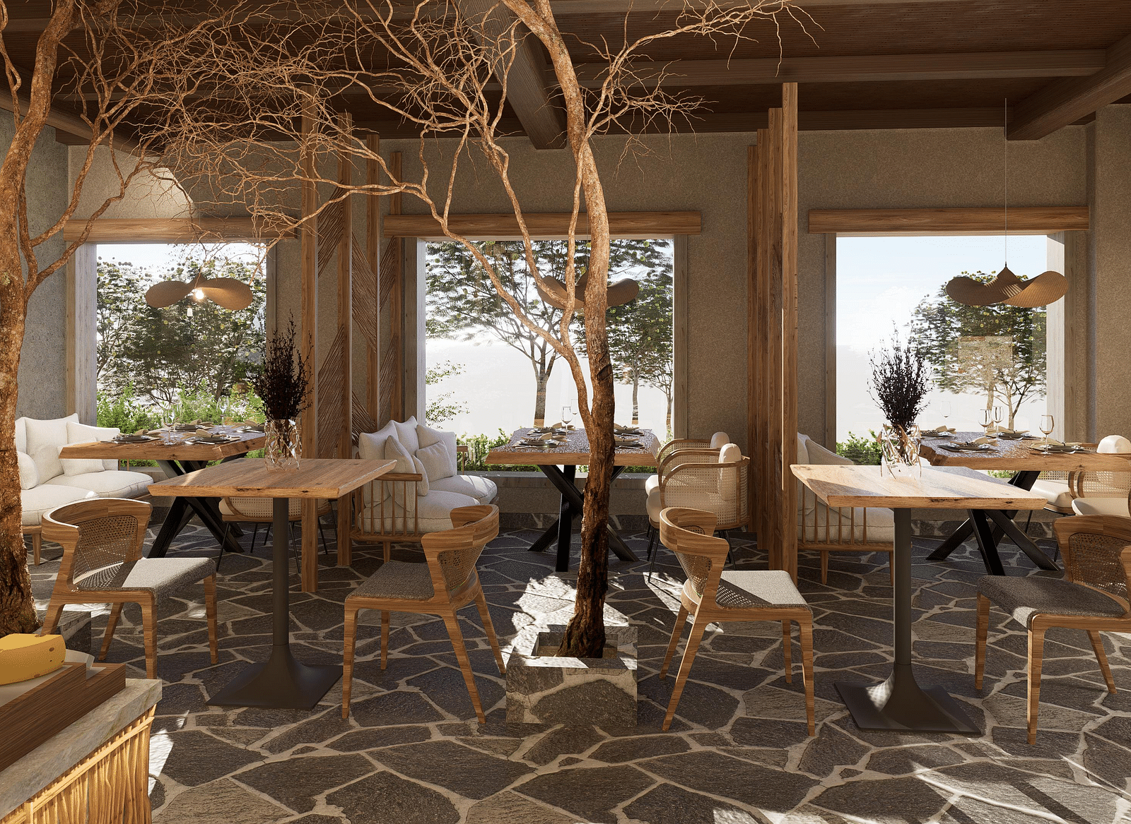 Side view of the restaurant at The Evren, Vagator, with arranged tables, chairs, and windows overlooking greenery.