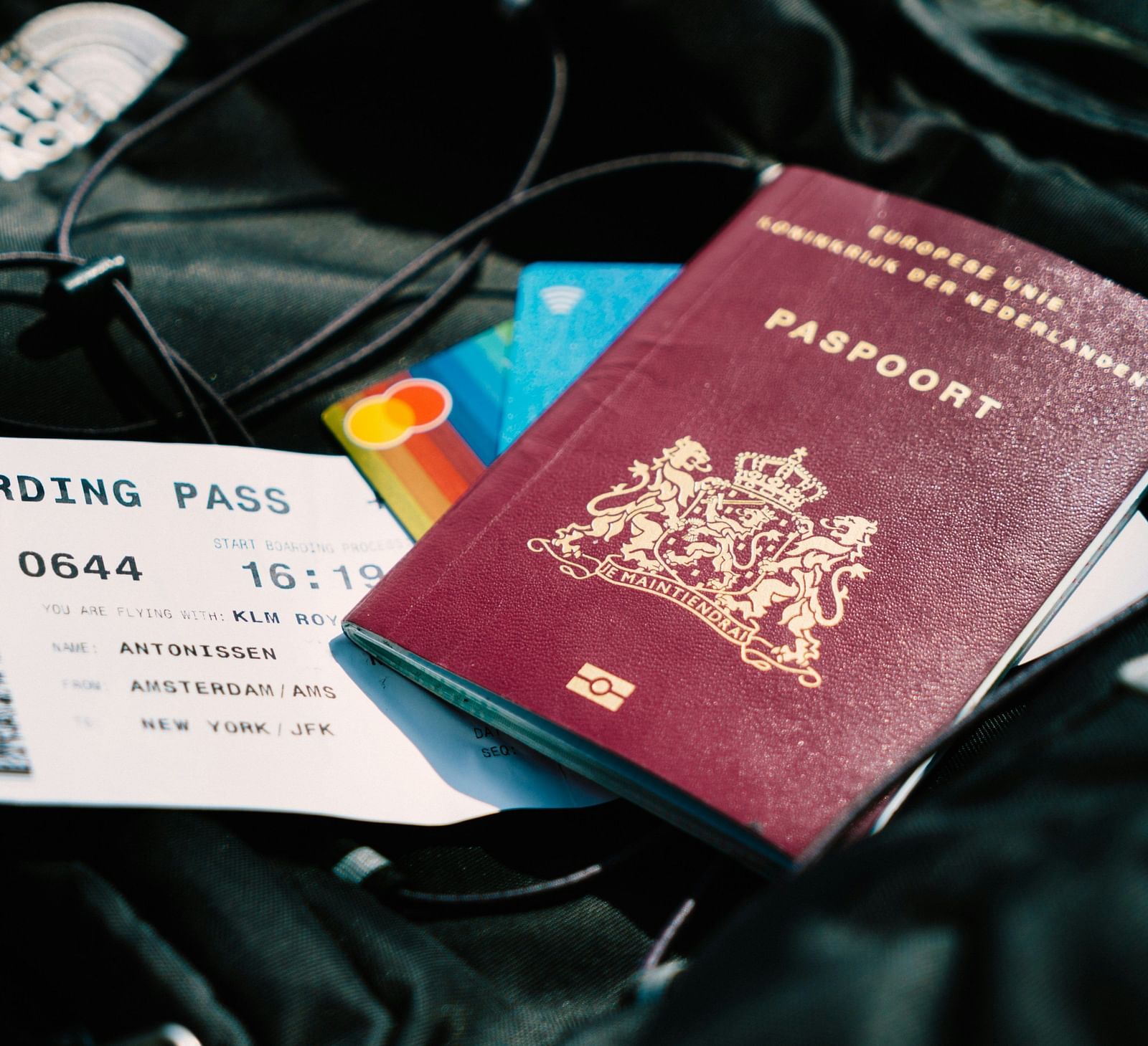 A travel-themed photo showing a European Union passport, a boarding pass and credit cards on top of a bag, suggesting preparation for a trip