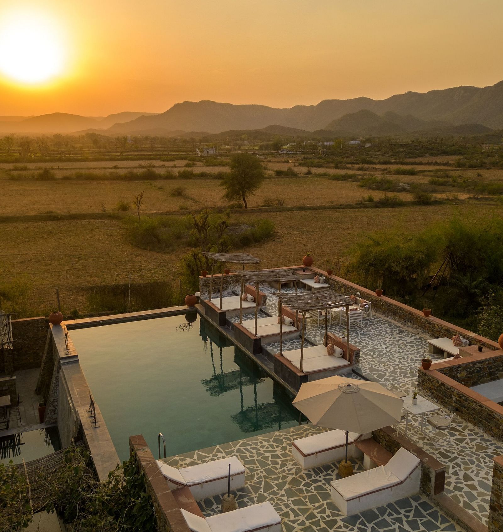 A serene sunset seen in the shot with a roof top swimming poll below it - Utsav Camp
