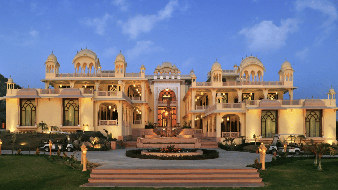 Facade of Rajasthali Resort & Spa Jaipur with plants in front and a clear sky in the background.