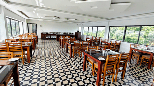 An overview of the seating arrangement with chequered floor, floor to ceiling windows on both sides and false ceiling at Abad Silvermist, Vagamon.