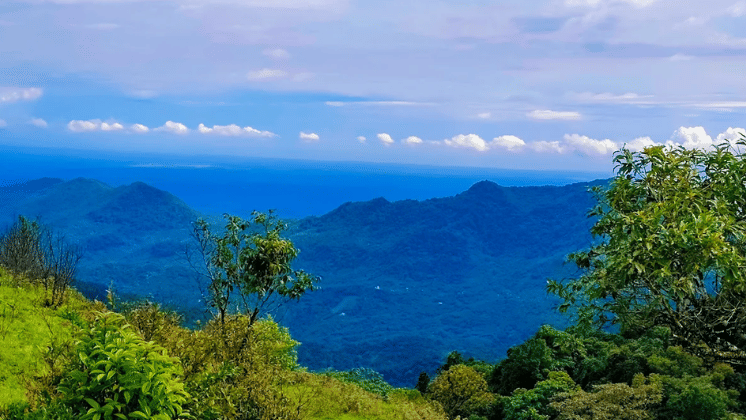 Wide view of layered hills and valleys under a soft blue sky.