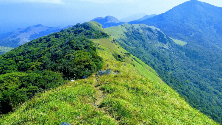 Narrow green mountain ridge with rolling hills fading into the distance.