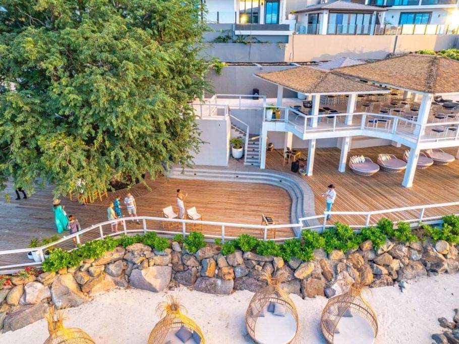 Elevated outdoor dining area with palm trees at Tamarind Hills Resort and Villas - Antigua, featuring multiple seating arrangements.