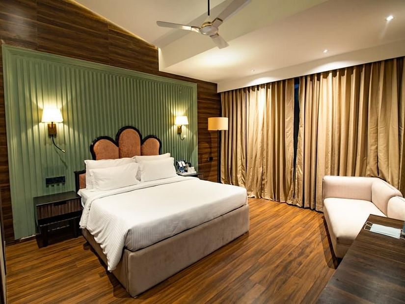 Luxury villa room with a cosy, spacious bed and a sofa in the corner at Wedlock Greens Hotel & Resort, Dhanbad