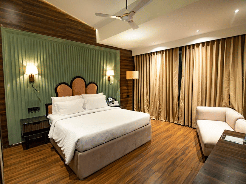 Luxury villa room with a cosy, spacious bed and a sofa in the corner at Wedlock Greens Hotel & Resort, Dhanbad