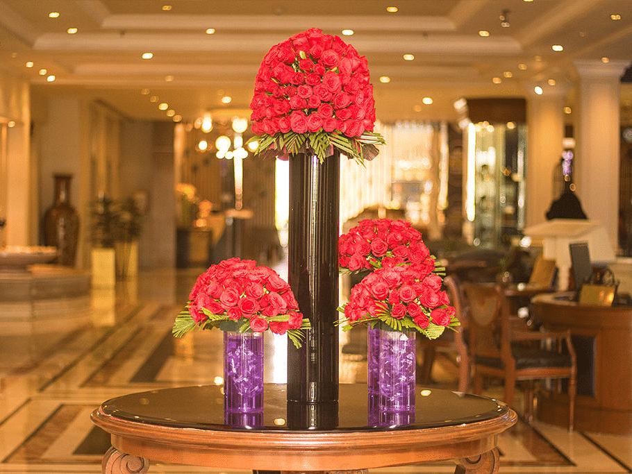 Elegant floral arrangement in a hotel lobby with red flowers in vases.