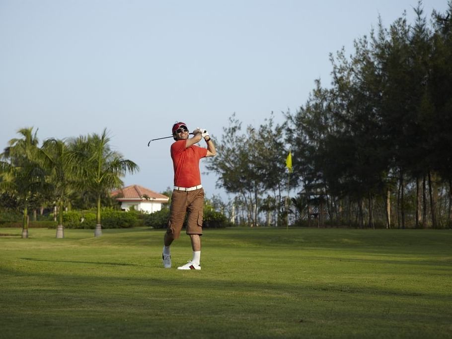 A man playing golf in a golf course.