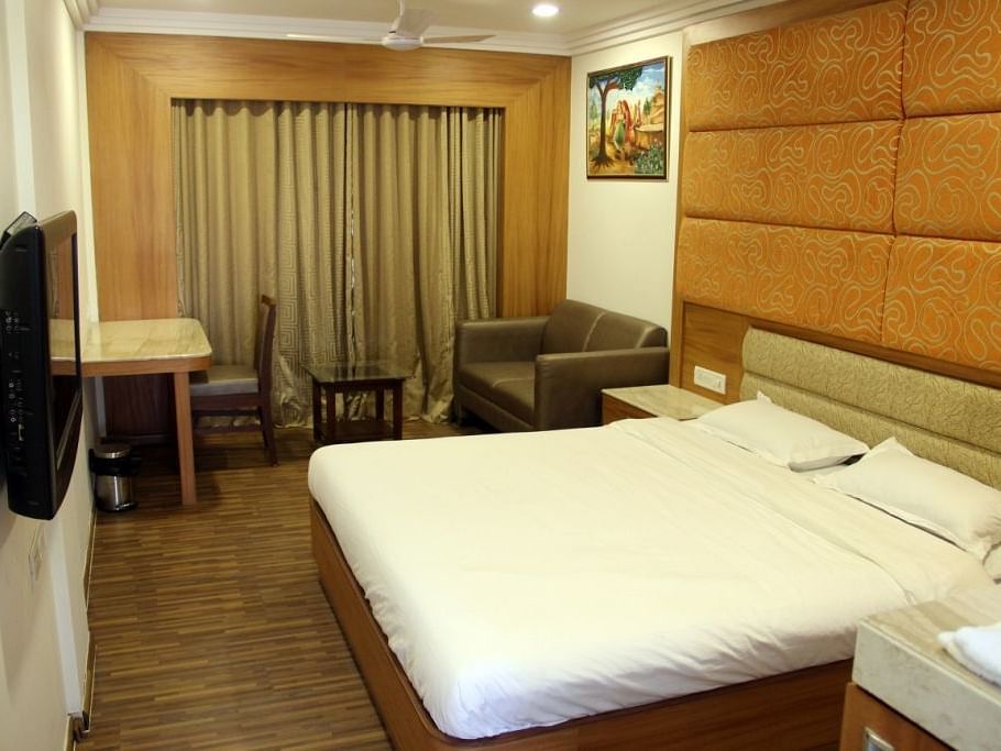 Well-lit hotel room with large bed, work desk, and TV