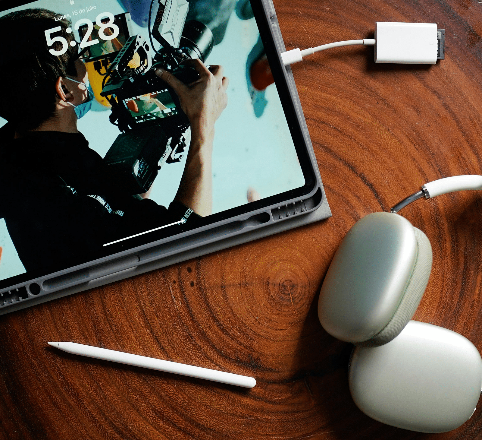 An image of a tablet, a stylus, and a pair of headphones are placed on a wooden table