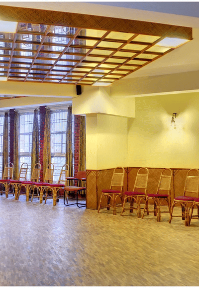 An image of a conference hall with a seating arrangement and wooden furnishing all around.