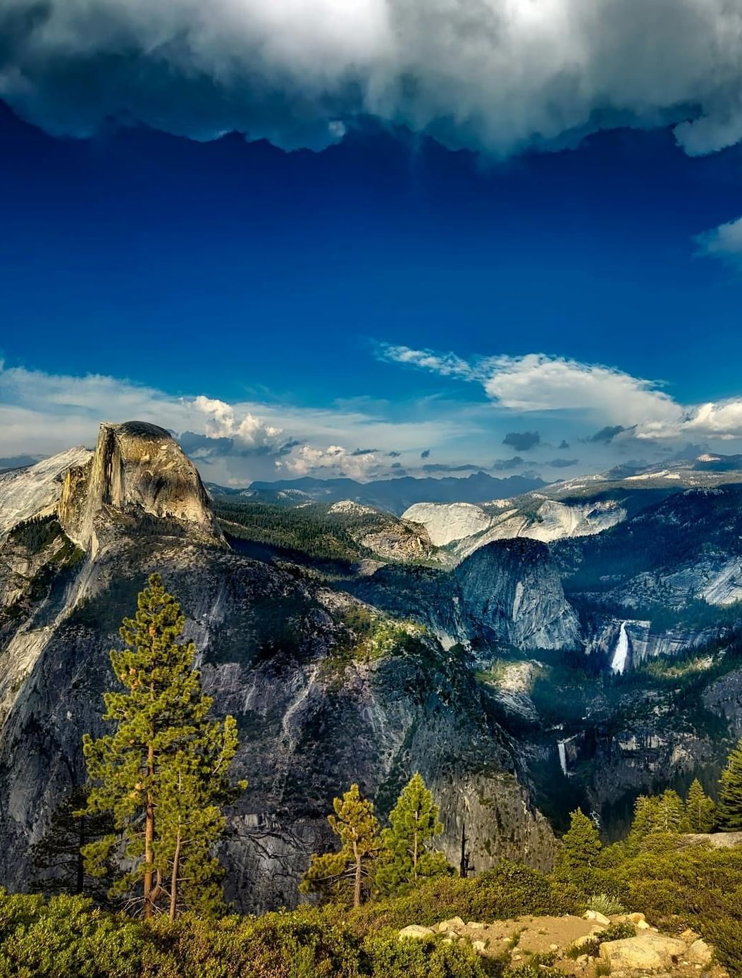 A far out view of a valley with white clouds on blue sky in the background.