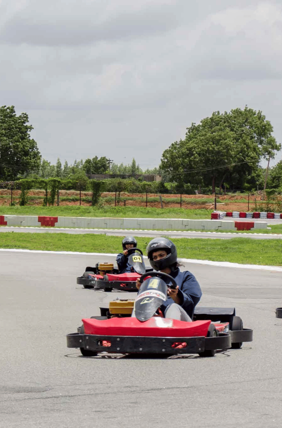 3 people enjoy racing go-karts around a curved outdoor track - District Gravity Adventure Park, Hyderabad
