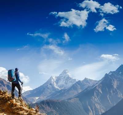 a man in his mountain climbing outfit standing at a peak watching the mountains across