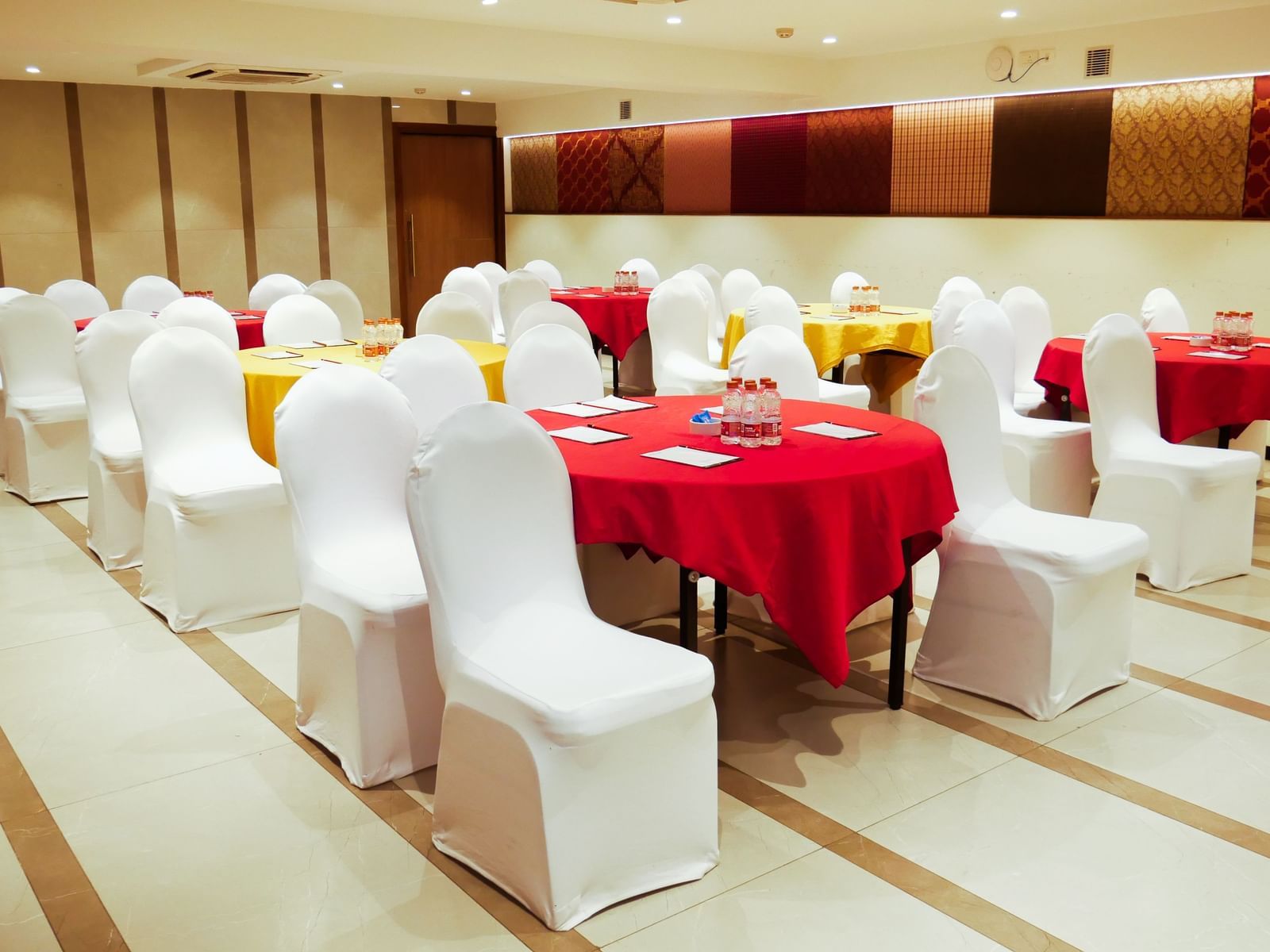 A well decorated banquet hall set up with round tables draped in red, ready for an event at Shilton Dee Cee.