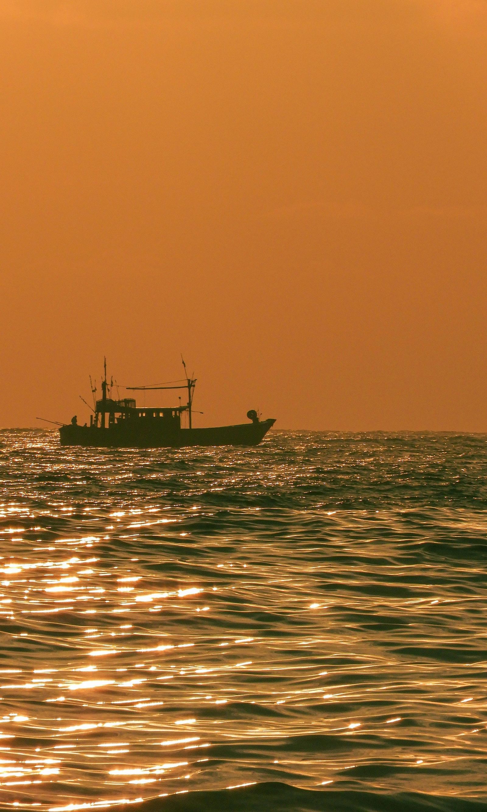 Sea waves with a boat during sunset.