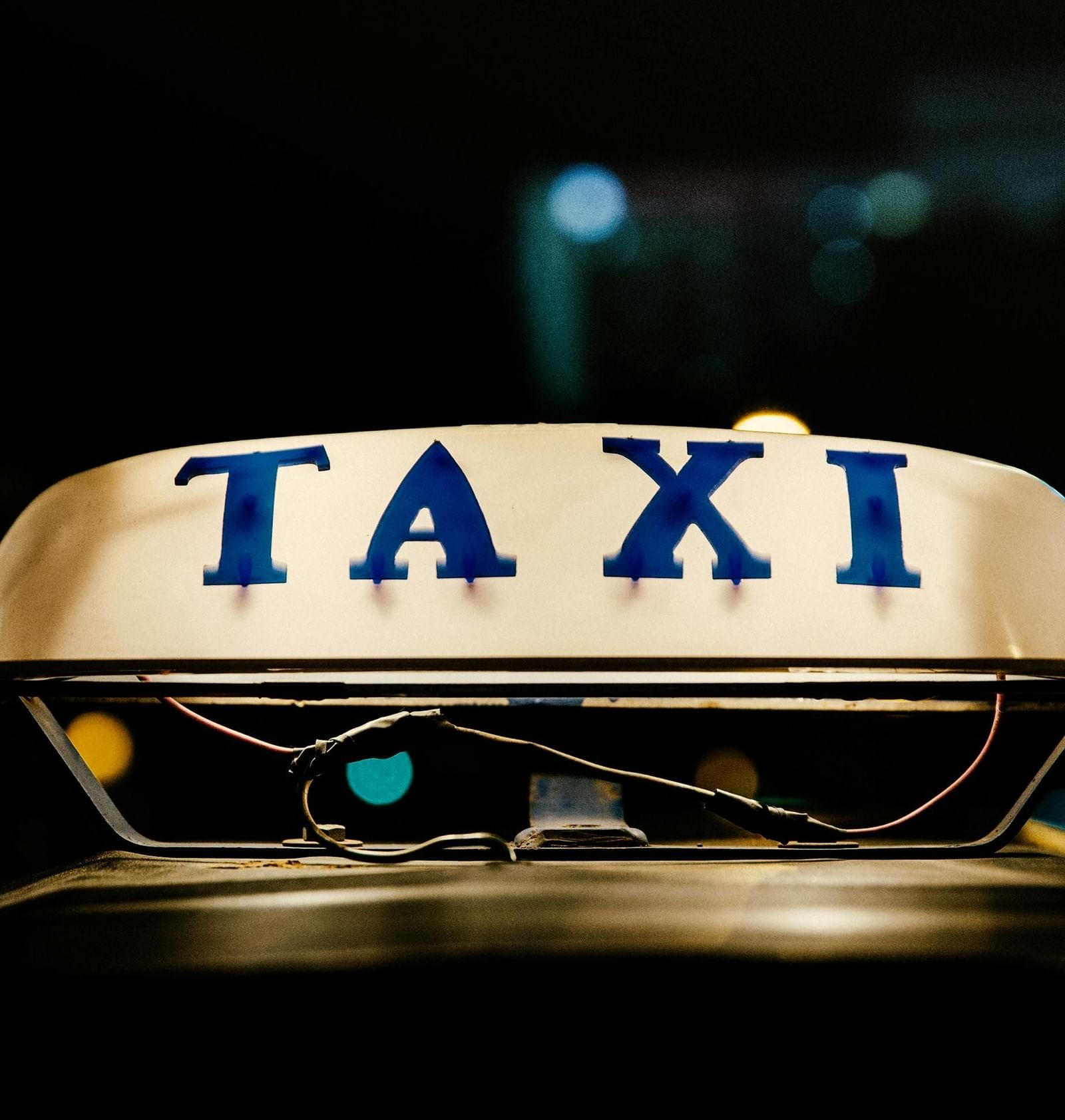 the illuminated sign on top of a taxi, with words TAXI written on it.