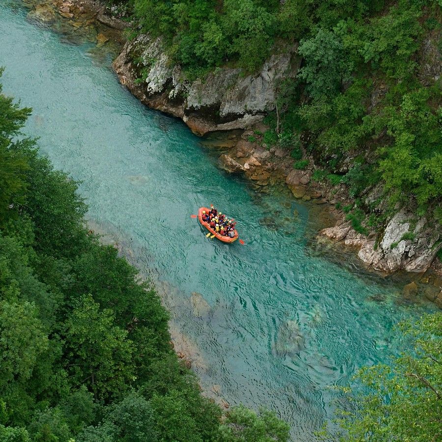 A top view of a valley featuring a winding river and a riverboat gliding along the water, surrounded by lush greenery and natural landscapes
