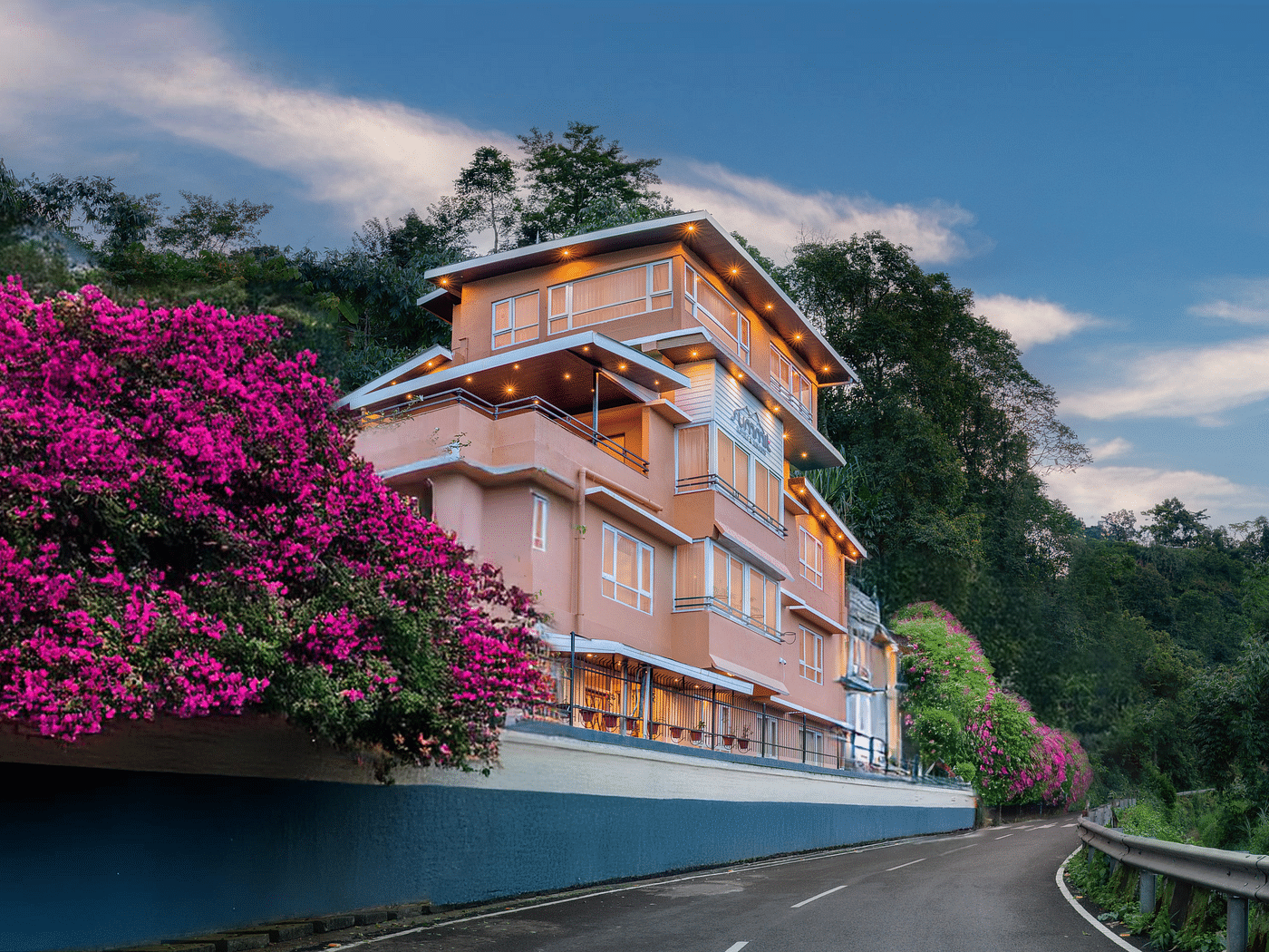 Facade of Summit Bougainvillea Tea Resort in Kurseong, framed by vibrant Bougainvillea plants, with a stunning sunset sky in the background