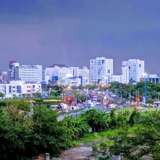 Evening cityscape with tall buildings, roads, and traffic lights.