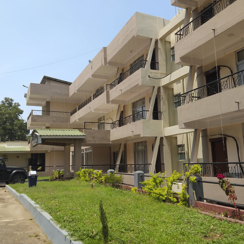 A view of the Polo Tura Hotel from a corner, showing its balconies, with a vehicle parked in front.