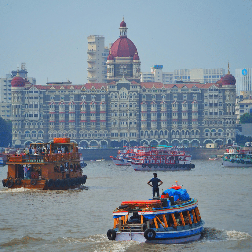 Taj Mahal Palace Hotel facade viewed from the Arabian Sea with colourful ferries and boats in the foreground