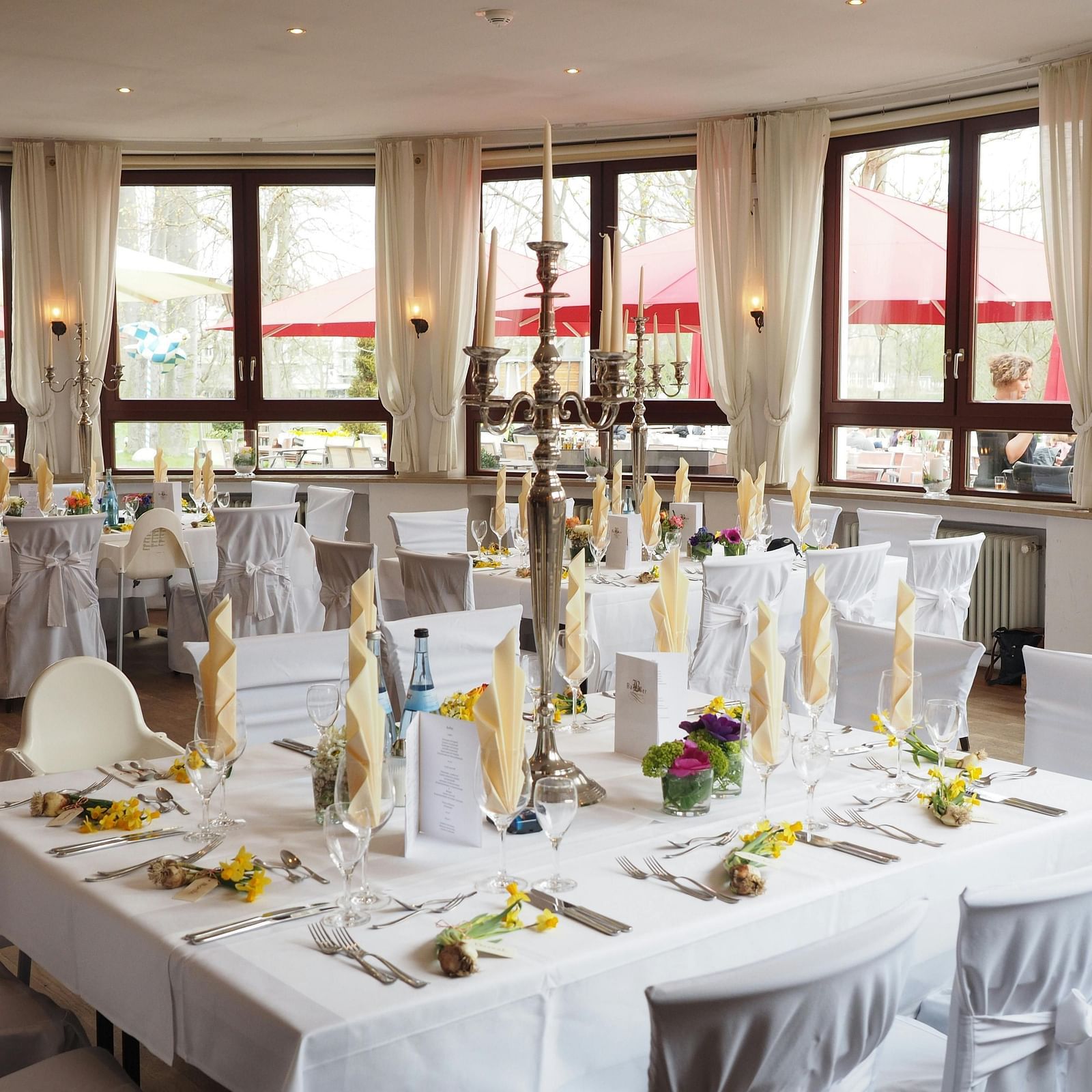 A formally set rectangular table with tall centerpieces in a dining area at Lords Plaza Surat.