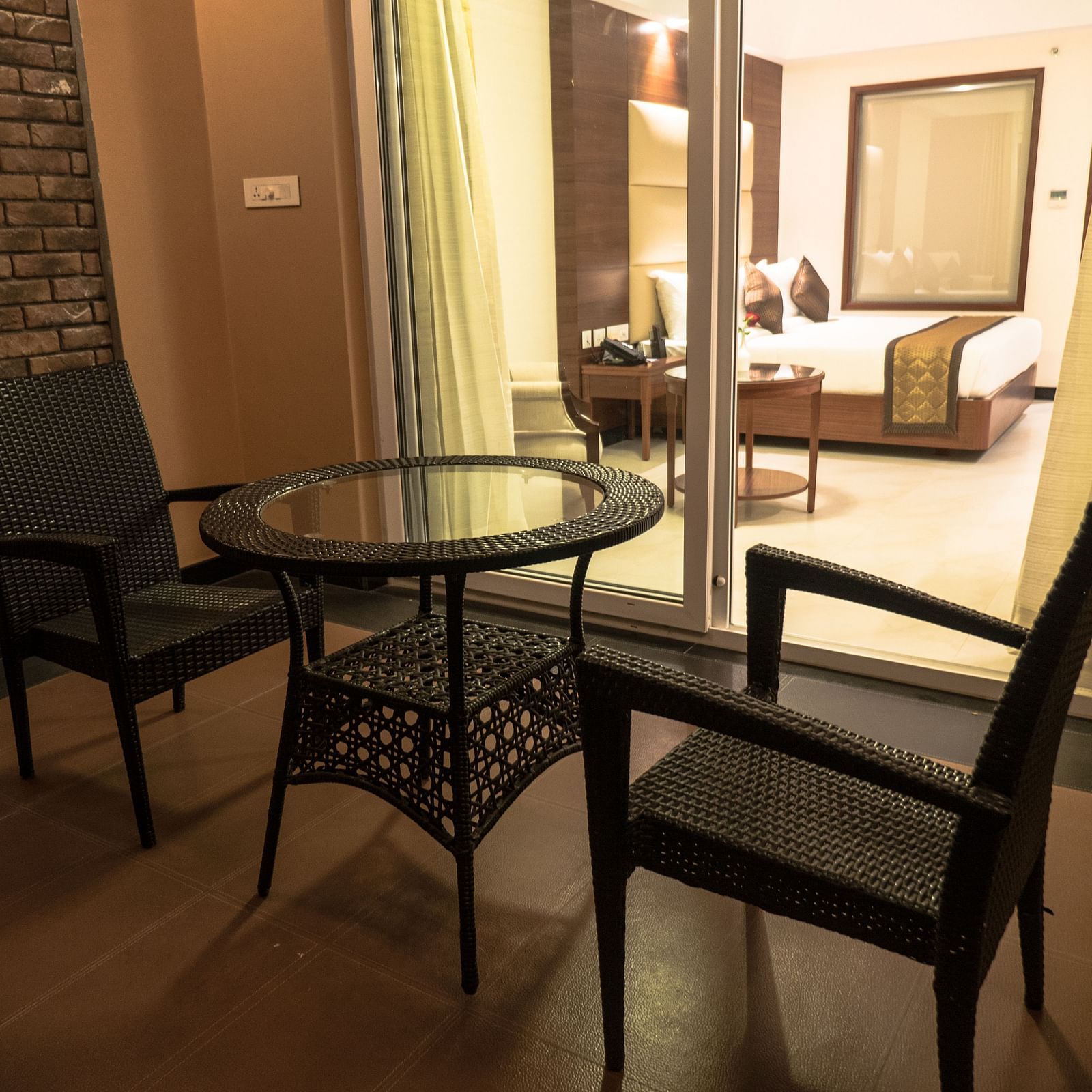Balcony view of a Luxury Room featuring two chairs and a table. The sliding glass door provides a view into the room.