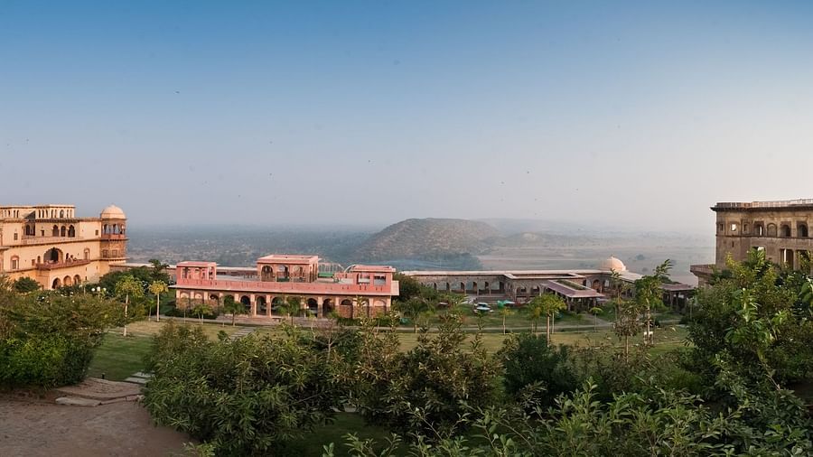 A panoramic view shows Tijara Fort-Palace amidst lush greenery under a clear sky in Alwar.