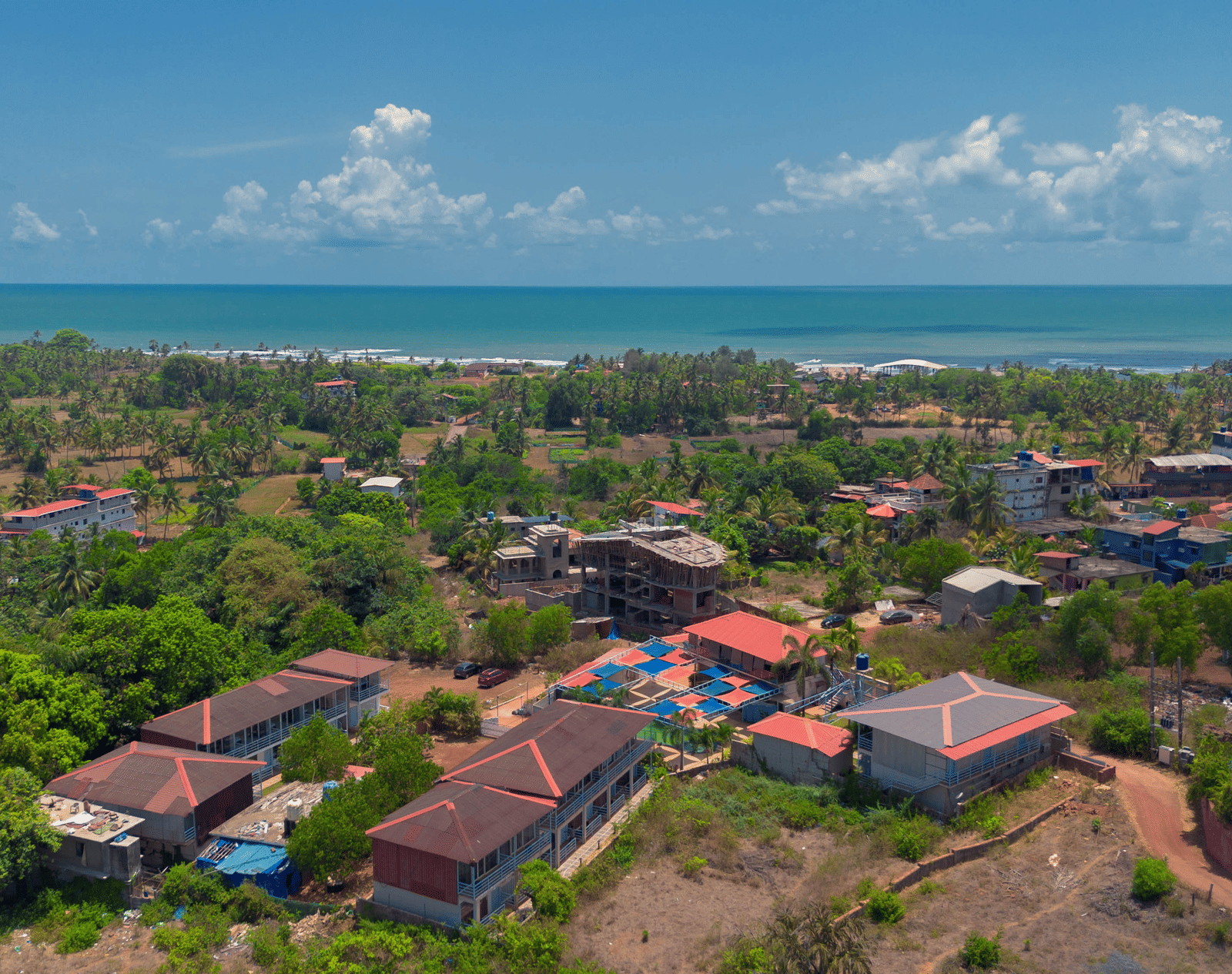 An aerial view of our resort, surrounded by lush green trees with Morjim Beach visible at the edge - Perfectstayz Koko Maya