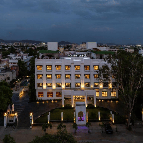 Golden Tulip, Udaipur exterior view with illuminated windows during dusk.