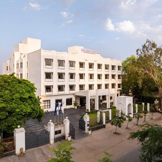 Daytime view of Golden Tulip, Udaipur building with driveway.