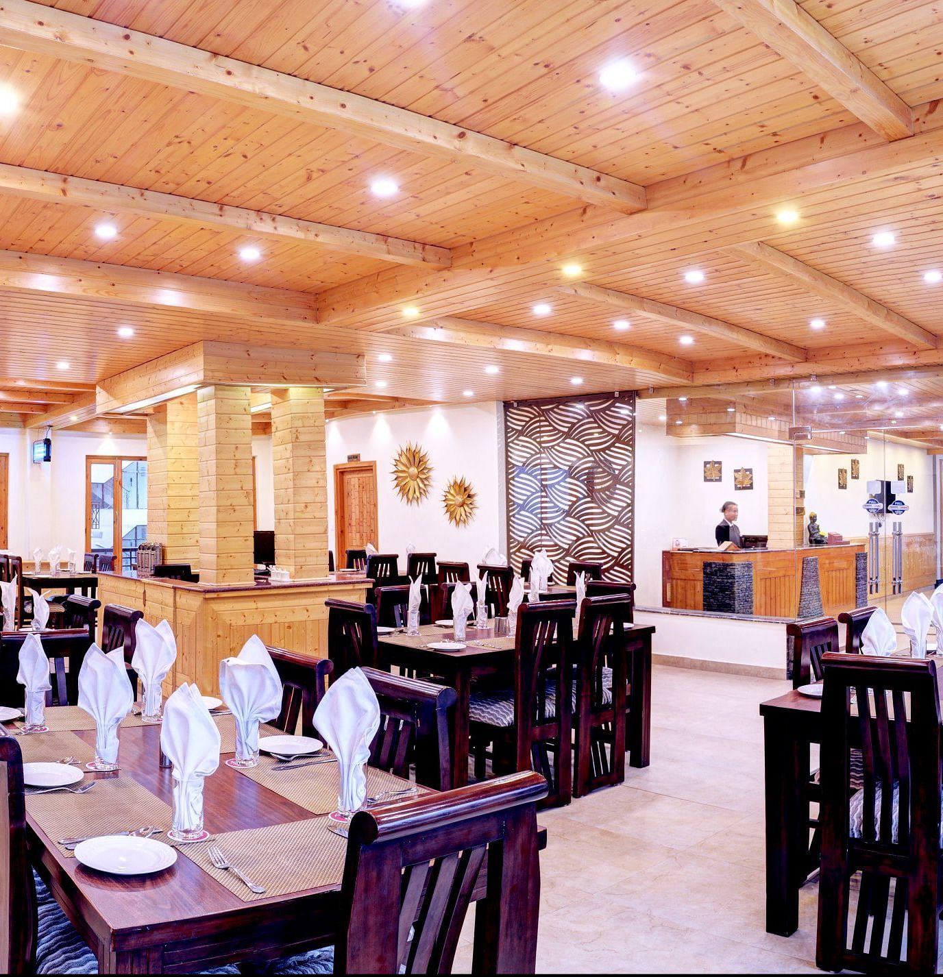 Image of a restaurant with tables and chairs and wooden ceiling at Summit Chandertal Regency Hotel & Spa