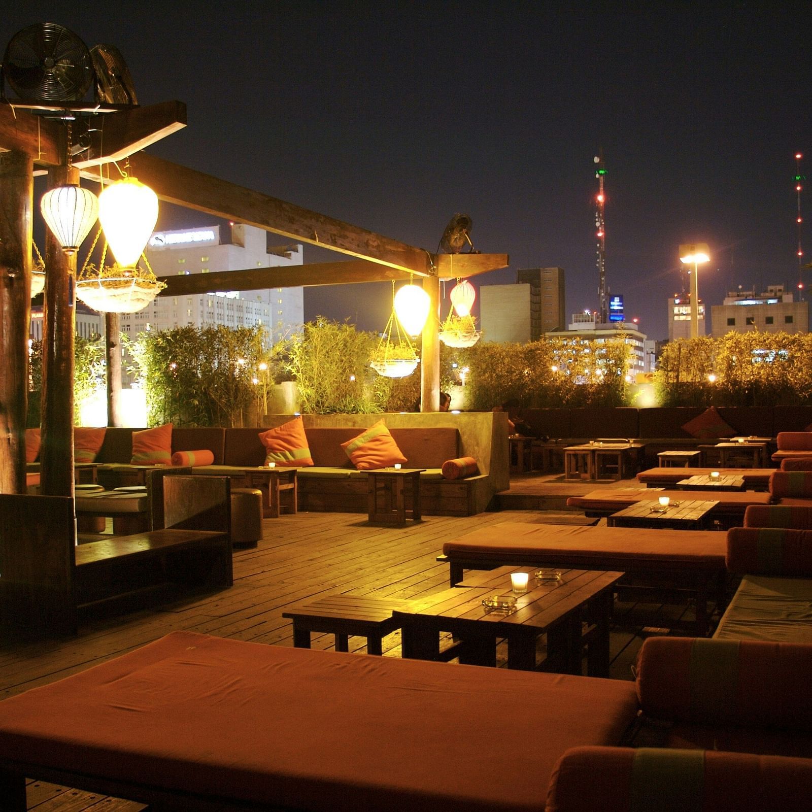 A well-lit rooftop dining space at night with tables and chairs spread across