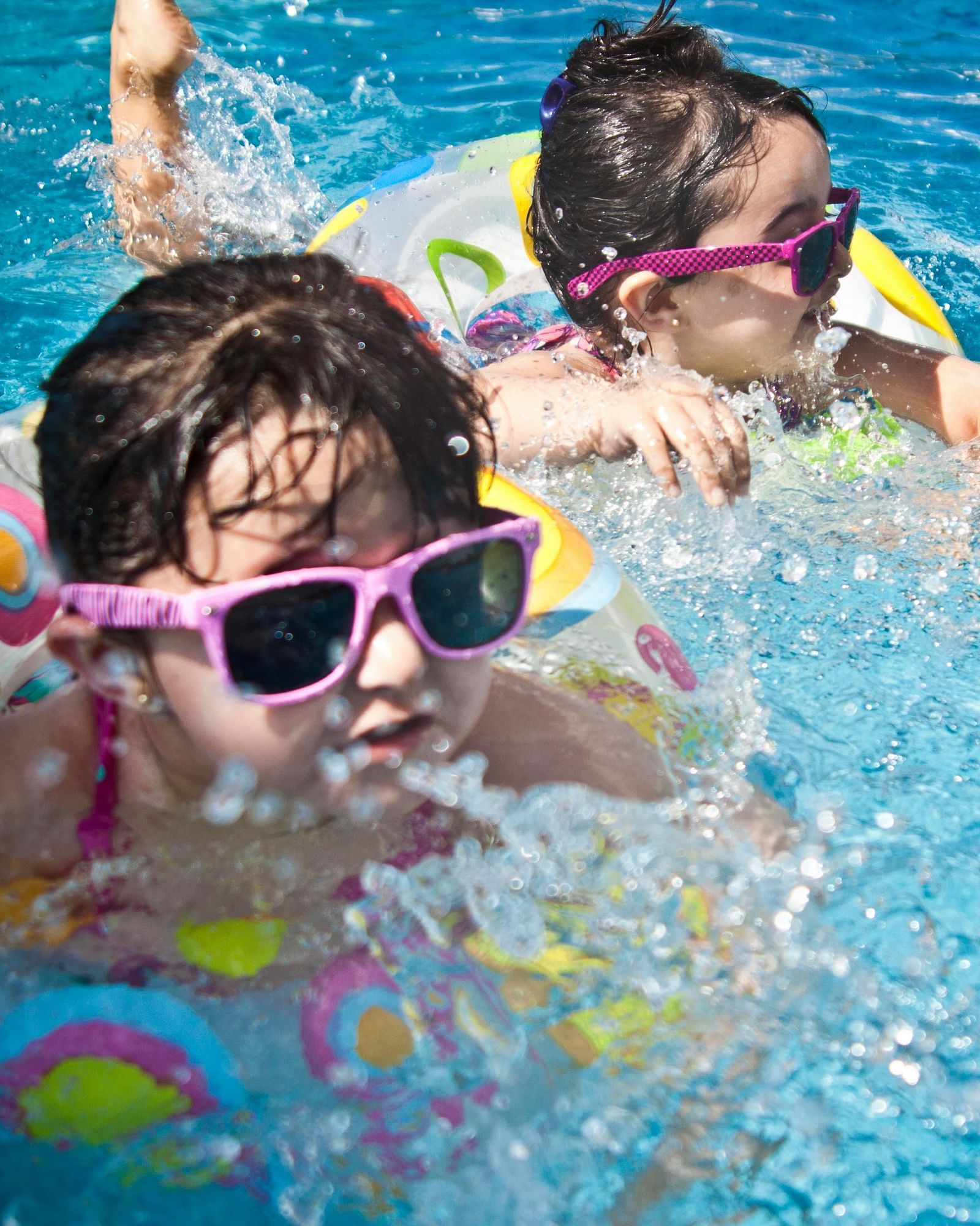 Two people wearing snorkels and goggles swimming in a bright blue swimming pool.