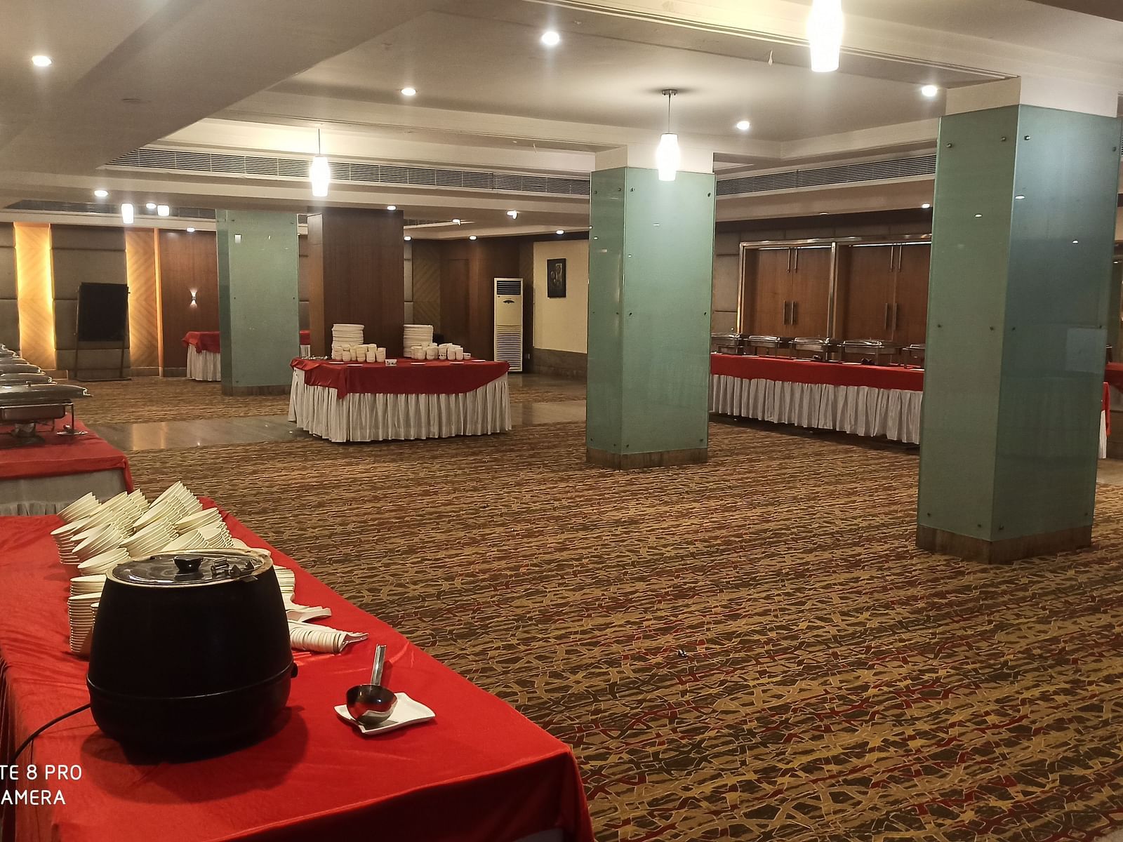 A banquet hall with buffet tables arranged along the sides of the room, with warm lighting and a carpeted floor - Lords Plaza Ankleshwar