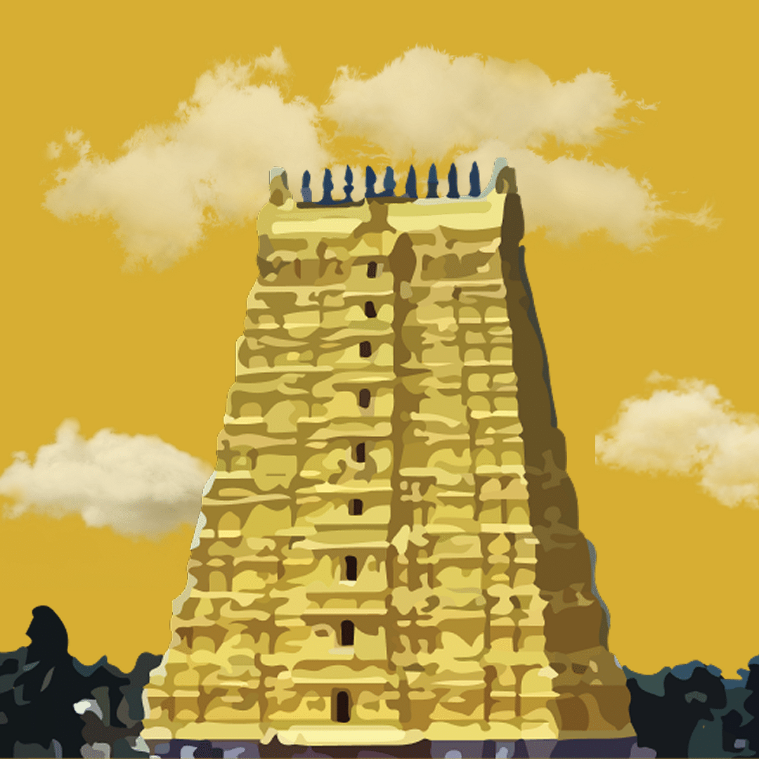 Striking yellow rajagopuram of a temple standing under golden skies.