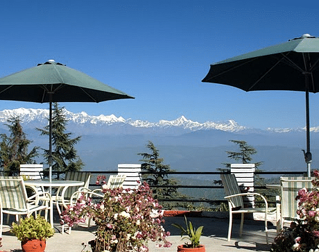 Outdoor dining area with tables and chairs on a balcony, overlooking a breathtaking mountain vista.
