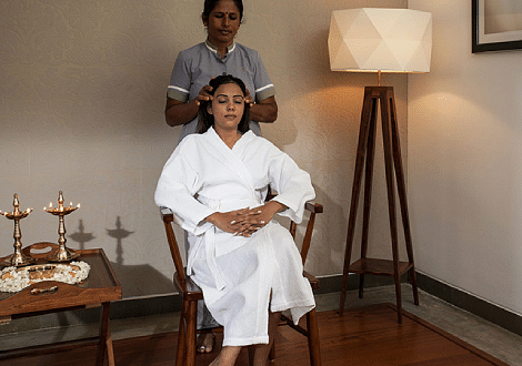 Two people sitting in chairs, one wearing a white robe, indoor setting, conversation - Shreyas Retreat