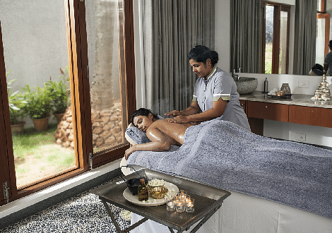 Person giving a massage to another person on a massage table, indoor setting, spa treatment - Shreyas Retreat
