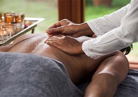 A person receiving a massage on their back, close-up shot, indoor setting - Shreyas Retreat