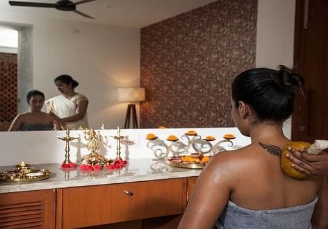A client receiving a soothing herbal oil massage in a serene spa setting - Shreyas Retreat