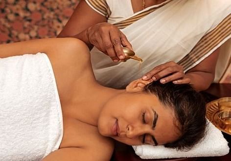 A close-up of a person receiving a head massage, white cloth, spa setting - Shreyas Retreat